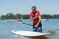 Man next to stand-up paddle board on lake Royalty Free Stock Photo