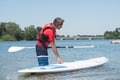 Man next to stand-up paddle board on lake Royalty Free Stock Photo