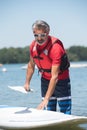 Man next to stand-up paddle board on lake Royalty Free Stock Photo