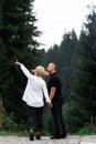 A man next to a woman, guy and a girl are standing close, touching each other, holding hand on forest background. Boy