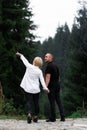 A man next to a woman, guy and a girl are standing close, touching each other, holding hand on forest background. Boy