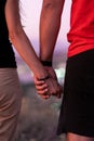 A man next to a woman, guy and a girl are standing close, touching each other, holding hands. The concept of first teenage love.