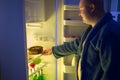 Man at night overstep and take whole chocolate cake from refrige