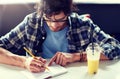 Man with notebook and juice writing at cafe