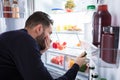 Man Noticing Smell Coming From Foul Food In Refrigerator