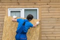 A man obstructs a window with a large piece of plywood before a natural disaster, a hurricane Royalty Free Stock Photo