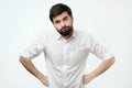 Annoyed man with beard, frowning and sulking from disappointment, holding hands on hips Royalty Free Stock Photo