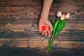 Man offers a heart and tulips on a brown wooden background. The concept of the holiday of Valentine`s Day, and International Wome Royalty Free Stock Photo