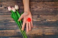 Man offers a heart and tulips on a brown wooden background. The concept of the holiday of Valentine`s Day, and International Wome Royalty Free Stock Photo