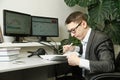 The man in the office for computer monitors studies records in a notebook