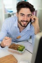 man in office eating salad while on phone Royalty Free Stock Photo