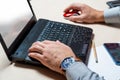 A man in the office typing on a laptop keyboard. Businessman at work. Hands close up