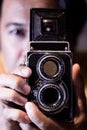 Man with old vintage camera in hands. Focus to man eyes. Vintage stylized photo of man photographer with old TLR Twin Lens Reflex Royalty Free Stock Photo