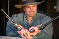 Man in old West clothing wielding two pistols