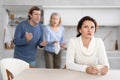 Man and old woman together scold thinking woman in kitchen