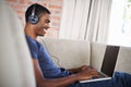 Man, online and music with laptop on sofa for movie streaming, podcast and internet games with listening. Happy, black Royalty Free Stock Photo