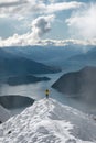 Man with open arms at peak of snowy mountain with amazing panoramic view of lakes and mountain range in winter