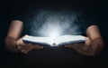 Man open magic book with growing lights and magic powder floating on the book, Learning, Education, Knowledge and religion Royalty Free Stock Photo