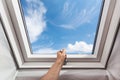 Man open new skylight mansard window in an attic room against blue sky. Royalty Free Stock Photo