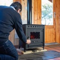 Man opening the door of a rustic cast iron stove to light the fire. Royalty Free Stock Photo
