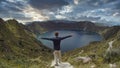 Man opening his arms and looking at a lake inside a volcano named Quilotoa. Ecuador, South America