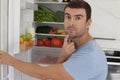 Man opening refrigerator door with doubts Royalty Free Stock Photo