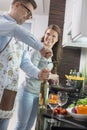 Man opening wine bottle while cooking with woman in kitchen Royalty Free Stock Photo