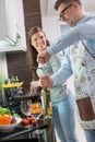 Man opening wine bottle while cooking with woman in kitchen Royalty Free Stock Photo