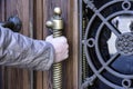 Man opens an ancient wooden door decorated with wrought iron elements and brass handle. Close-up Royalty Free Stock Photo