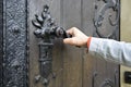Man opens an ancient wooden door decorated with wrought iron elements Royalty Free Stock Photo