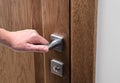 The man opens the door. Close - up of hand and door handle, white wall Royalty Free Stock Photo