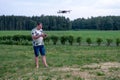 A man operating the drone by remote control on the meadow near forest Royalty Free Stock Photo