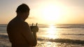 Man operating a drone with remote control. Quadro copter drone flying over sunset ocean Royalty Free Stock Photo