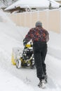 Man operating snow blower to remove snow on driveway. Man using a snowblower. A man cleans snow from sidewalks with snowblower. Royalty Free Stock Photo