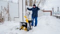 Man operating snow blower to remove snow on driveway Royalty Free Stock Photo