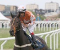 Man in orange clothes riding a race horse