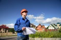 Man in a orange helmet with the plan of construction Royalty Free Stock Photo