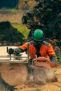 A man in an orange jacket cuts boards with an alaskan portable chainsaw mill Royalty Free Stock Photo
