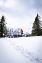 Man with orange jacket snowshoeing in Hohentauern on cloudy winterday