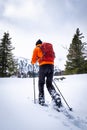 Man with orange jacket snowshoeing in Hohentauern on cloudy winterday