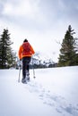 Man with orange jacket snowshoeing in Hohentauern on cloudy winterday