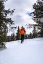 Man with orange jacket snowshoeing in Hohentauern on cloudy winterday