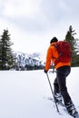 Man with orange jacket snowshoeing in Hohentauern on cloudy winterday