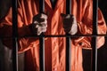 man in orange jumpsuit clenching bars of a jail cell Royalty Free Stock Photo