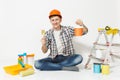 Man in orange protective helmet sitting with paint brush, can, instruments for renovation apartment isolated on white Royalty Free Stock Photo