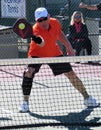 Man in orange shirt and white cap Showing skills in Pickleball Tournament