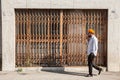 Man with orange turban in front of shuttered shop