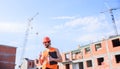 Man orange vest and helmet works at construction site. Contractor control according to plan. Control construction Royalty Free Stock Photo