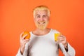 Man with oranges and orange juice in hands. Handsome young man hold fresh natural orange on orange backgroung isolated.