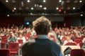 A man, the orator, sits poised before a vast crowd, delivering a lecture with passion and conviction as the audience